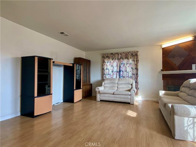 living room featuring a brick fireplace and wood-type flooring