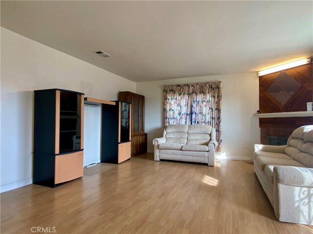 living area with baseboards, light wood-style flooring, and visible vents
