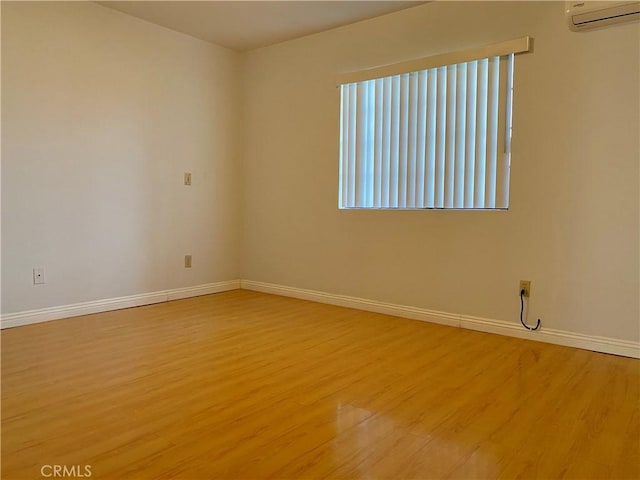 spare room featuring a wall mounted AC and light wood-type flooring