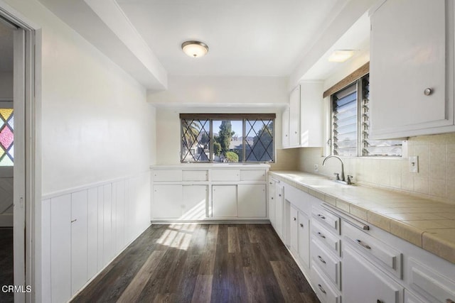 kitchen featuring sink, white cabinets, decorative backsplash, tile counters, and dark wood-type flooring