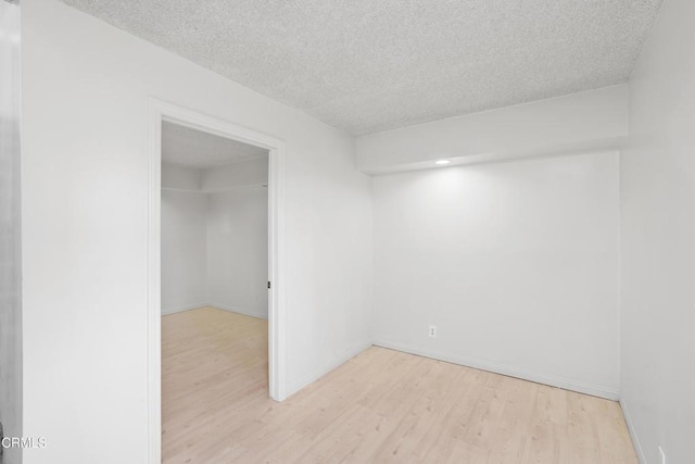 spare room featuring light hardwood / wood-style floors and a textured ceiling