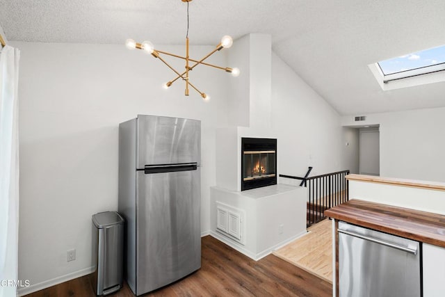 kitchen with dark hardwood / wood-style floors, appliances with stainless steel finishes, lofted ceiling with skylight, and butcher block countertops