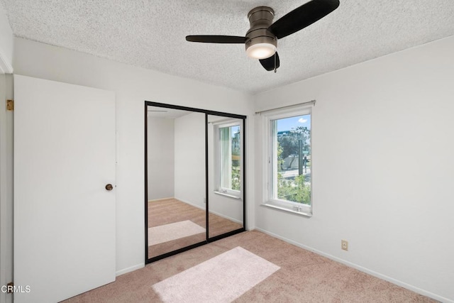 unfurnished bedroom with ceiling fan, a closet, light carpet, and a textured ceiling