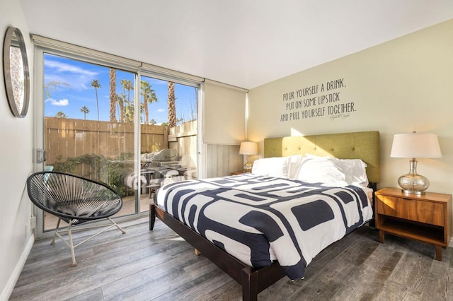 bedroom with dark hardwood / wood-style floors, access to exterior, and a wall of windows