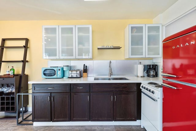 kitchen with sink, refrigerator, dark brown cabinets, white range with electric stovetop, and backsplash