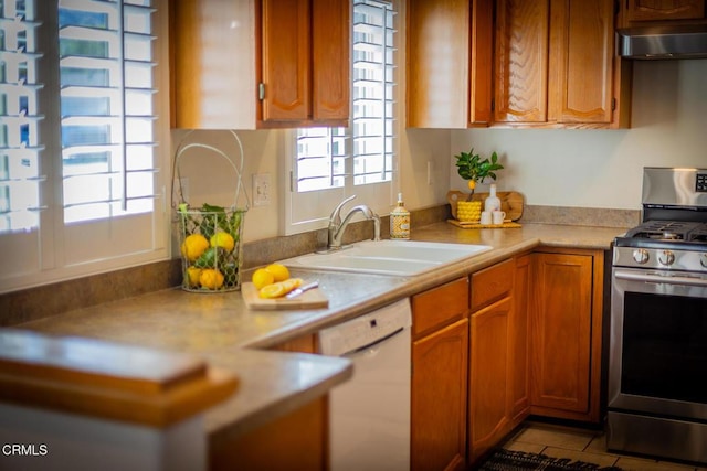 kitchen featuring sink, light tile patterned floors, white dishwasher, and stainless steel gas stove