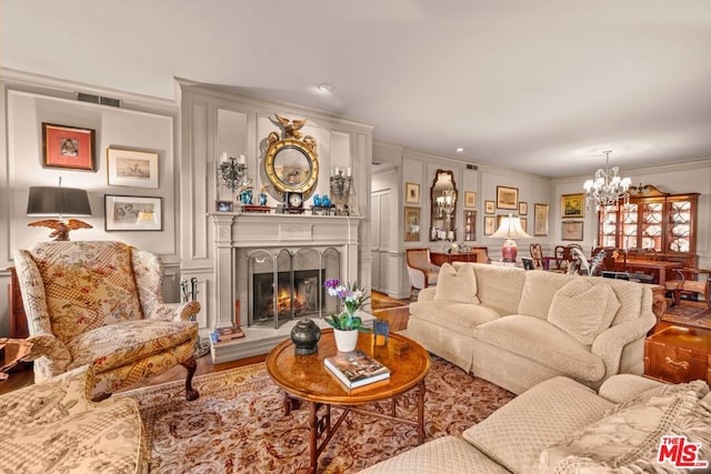 living room featuring ornamental molding, a chandelier, and wood-type flooring