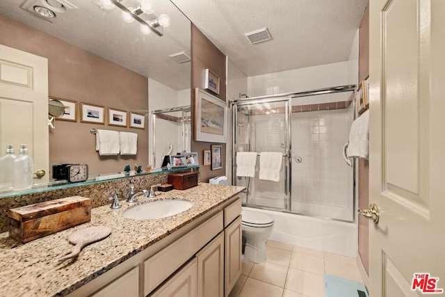 full bathroom featuring tile patterned floors, toilet, a textured ceiling, vanity, and enclosed tub / shower combo