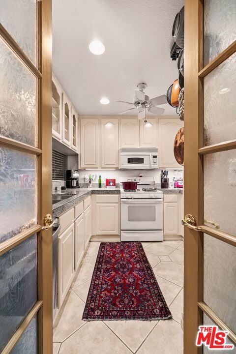 kitchen with light tile patterned floors, white appliances, sink, and ceiling fan