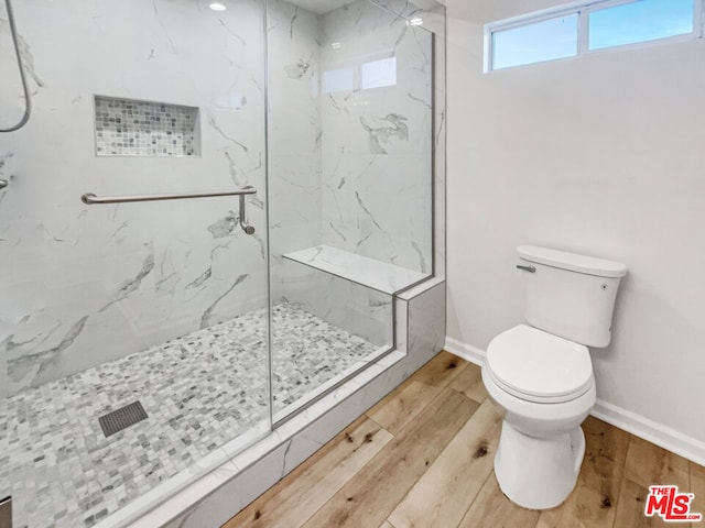 bathroom featuring wood-type flooring, a tile shower, and toilet