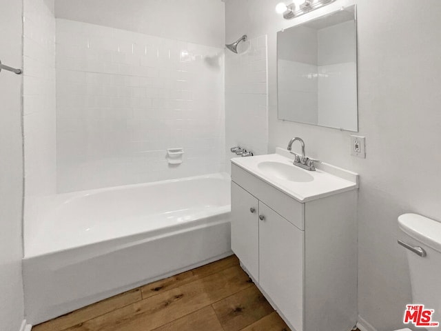 full bathroom featuring tiled shower / bath, vanity, toilet, and hardwood / wood-style floors