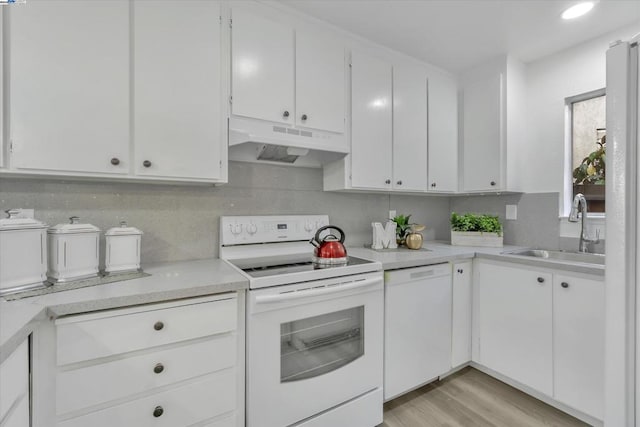 kitchen with white cabinetry, white appliances, sink, and backsplash