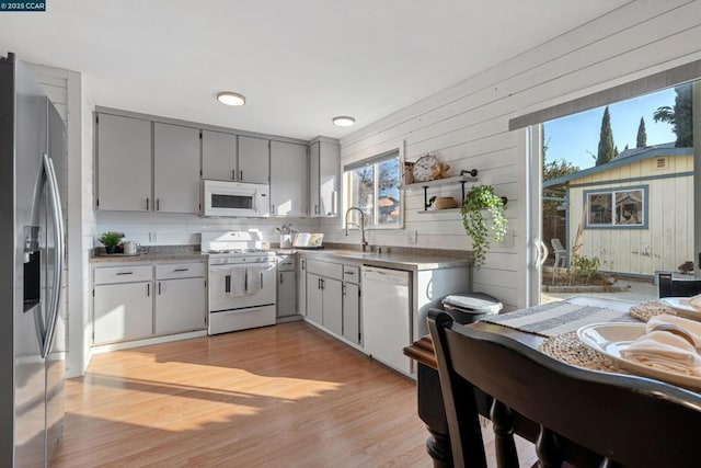 kitchen featuring gray cabinetry, sink, white appliances, and light hardwood / wood-style floors