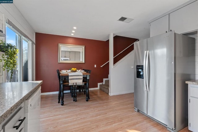 kitchen with white cabinetry, dishwasher, stainless steel fridge with ice dispenser, and light hardwood / wood-style flooring