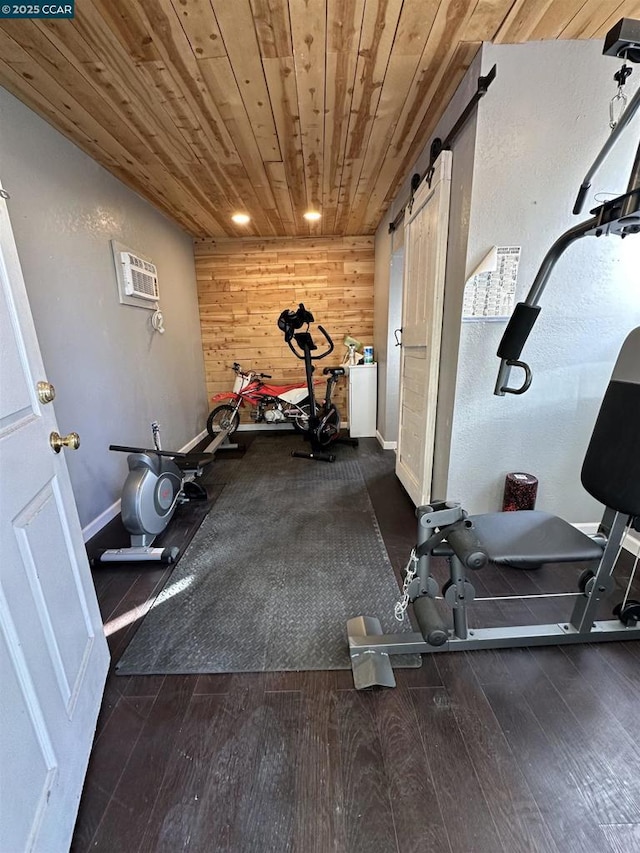 workout room featuring dark wood-type flooring, a wall mounted AC, wooden ceiling, wooden walls, and a barn door