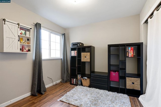 bedroom with dark wood-type flooring and a barn door