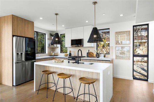 kitchen with light countertops, appliances with stainless steel finishes, modern cabinets, and a breakfast bar