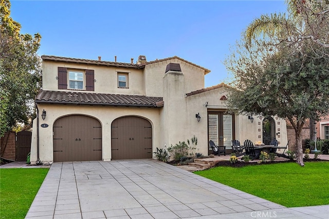 mediterranean / spanish home featuring a garage and a front lawn