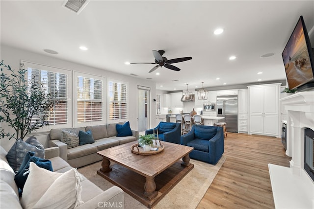 living room featuring ceiling fan and light hardwood / wood-style floors