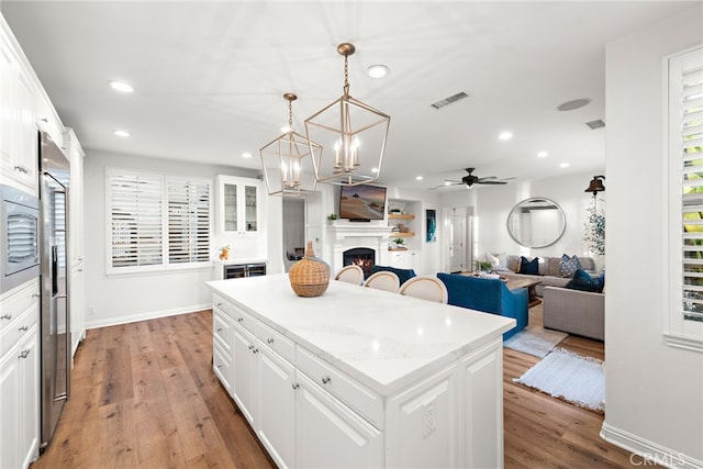 kitchen featuring a center island, light hardwood / wood-style flooring, white cabinets, and decorative light fixtures