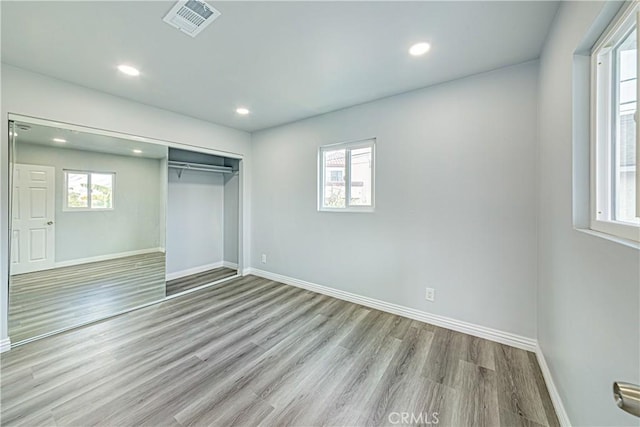 unfurnished bedroom with multiple windows, light hardwood / wood-style floors, and a closet