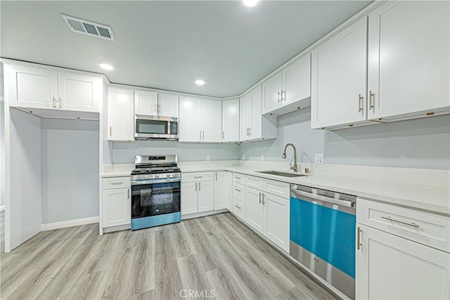 kitchen featuring light wood-type flooring, stainless steel appliances, sink, and white cabinets