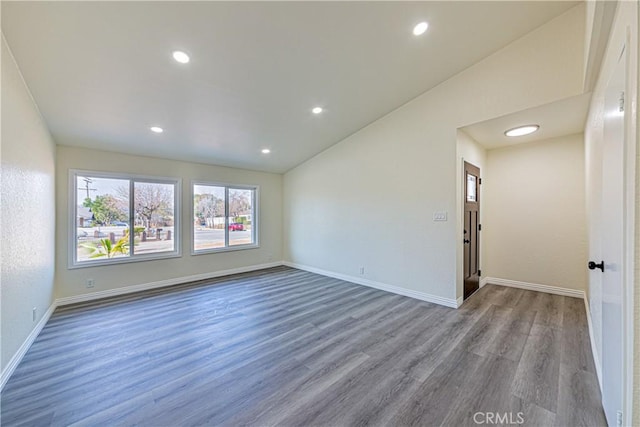 spare room featuring vaulted ceiling and light hardwood / wood-style floors