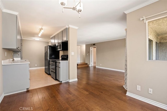 kitchen with sink, crown molding, light wood-type flooring, and appliances with stainless steel finishes