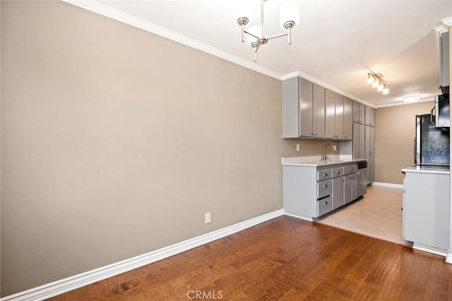 kitchen featuring gray cabinets, sink, ornamental molding, stainless steel dishwasher, and light hardwood / wood-style flooring