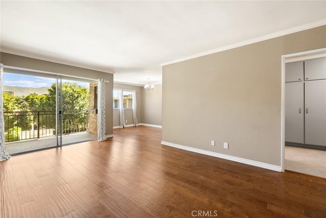 spare room with crown molding, hardwood / wood-style floors, and a notable chandelier