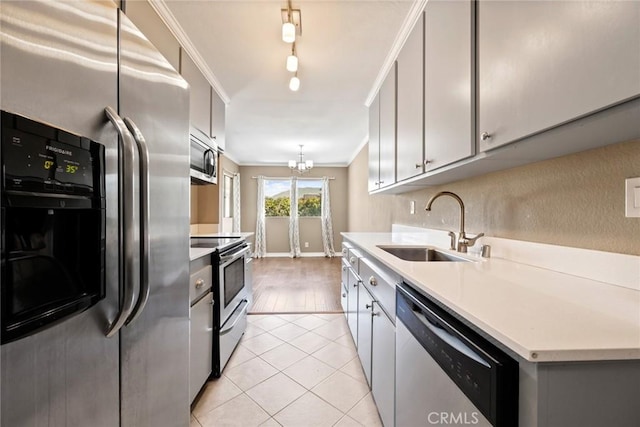 kitchen with sink, gray cabinetry, light tile patterned floors, ornamental molding, and appliances with stainless steel finishes