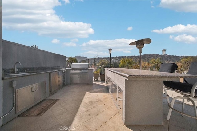 view of patio / terrace featuring a grill, an outdoor kitchen, an outdoor wet bar, and a mountain view