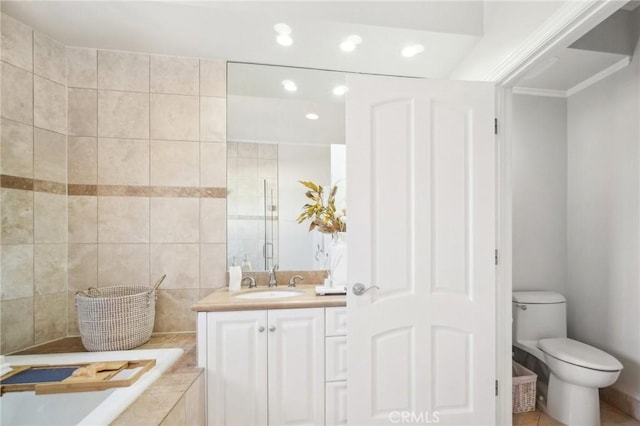 bathroom featuring vanity, tiled bath, and toilet