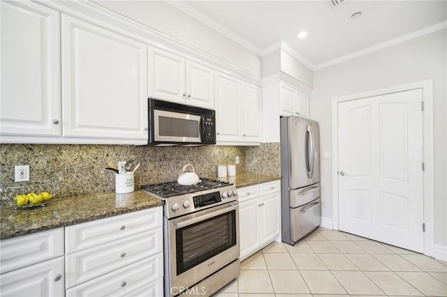 kitchen with crown molding, stainless steel appliances, dark stone counters, and white cabinets