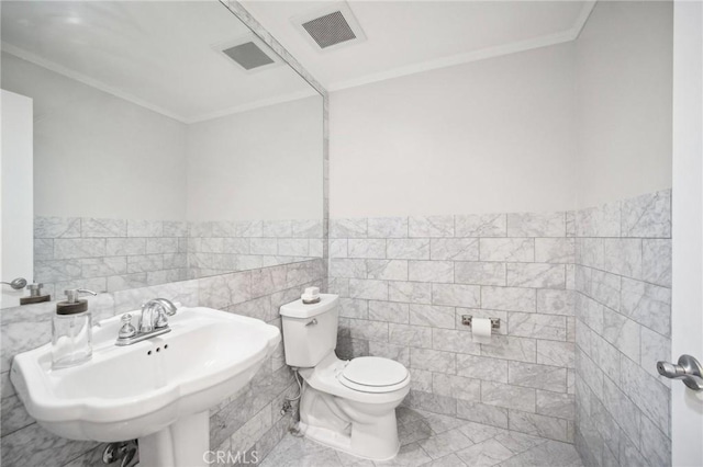 bathroom with crown molding, toilet, sink, and tile walls