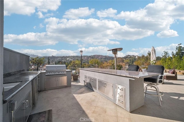 view of patio / terrace with an outdoor bar, an outdoor kitchen, a mountain view, and area for grilling