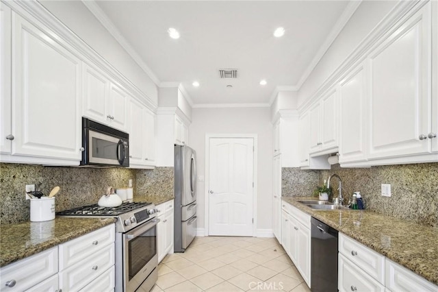 kitchen featuring sink, white cabinetry, ornamental molding, appliances with stainless steel finishes, and dark stone counters