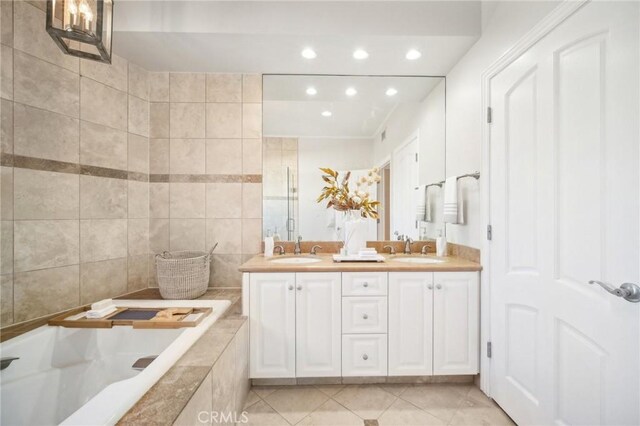 bathroom featuring vanity, tile patterned flooring, tile walls, and tiled tub