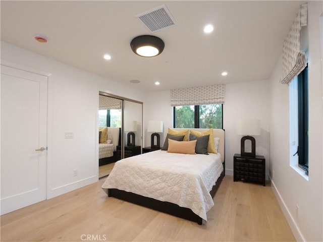 bedroom with multiple windows, a closet, and light hardwood / wood-style flooring