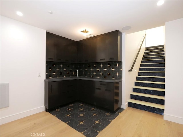 bar featuring hardwood / wood-style flooring, dark brown cabinets, and backsplash