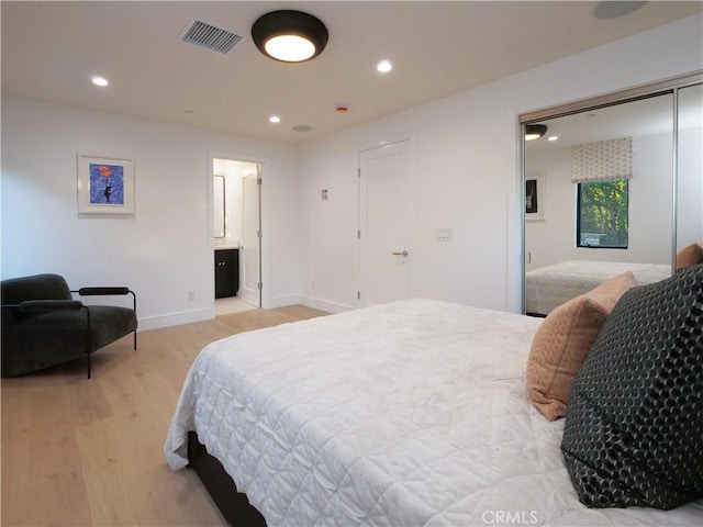 bedroom with ensuite bath and light wood-type flooring