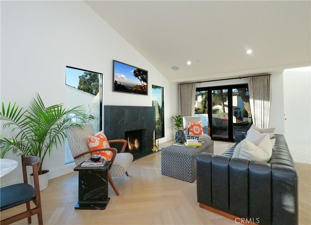 living room featuring high vaulted ceiling, a premium fireplace, and light parquet flooring