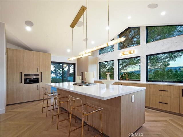 kitchen featuring pendant lighting, light parquet flooring, a large island, and a kitchen breakfast bar