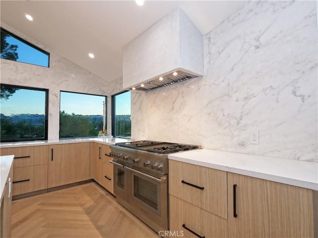 kitchen with premium range hood, lofted ceiling, range with two ovens, light parquet floors, and light brown cabinets