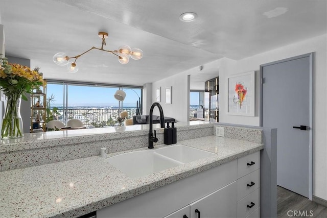 kitchen featuring pendant lighting, sink, dark hardwood / wood-style floors, light stone countertops, and white cabinets