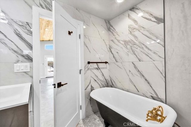 bathroom with vanity, a bath, and tile walls