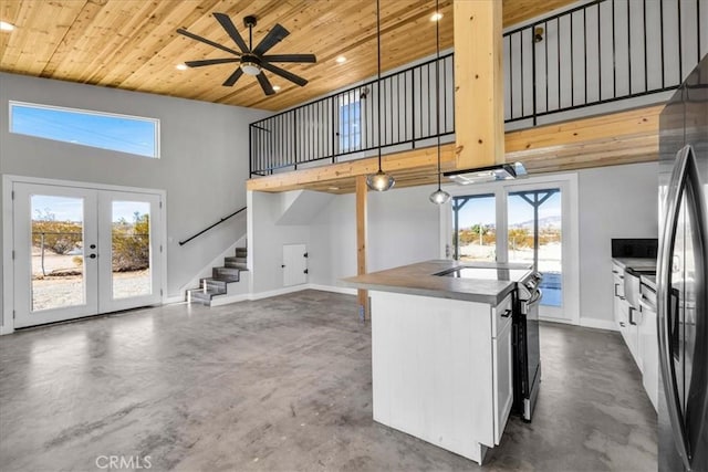 kitchen with range with electric cooktop, pendant lighting, white cabinetry, concrete floors, and wooden ceiling