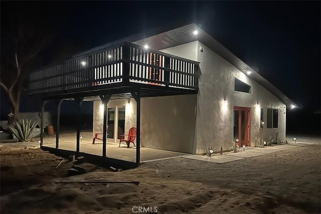 back house at twilight featuring a patio area