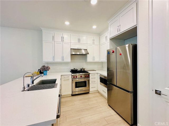 kitchen featuring appliances with stainless steel finishes, sink, light hardwood / wood-style flooring, and white cabinets