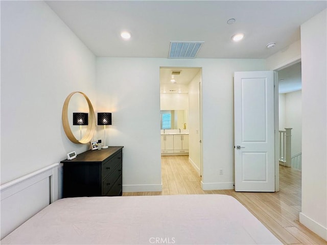 bedroom with connected bathroom and light hardwood / wood-style floors